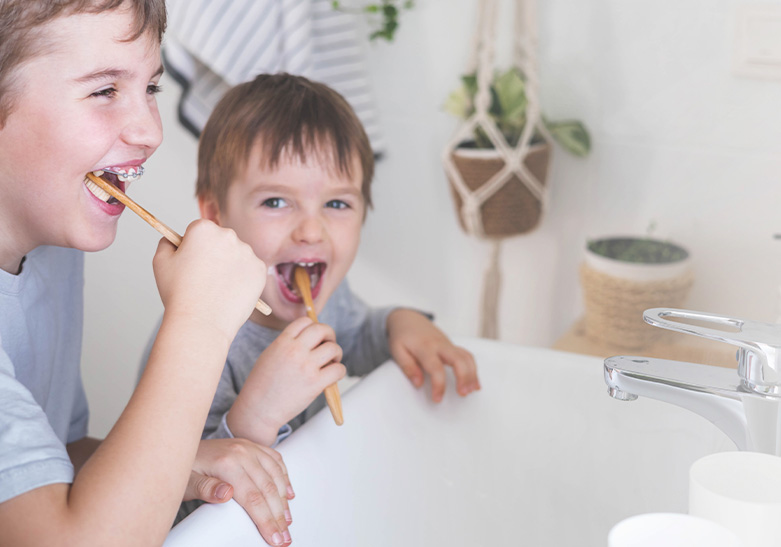 niños lavándose los dientes en el baño frente al espejo